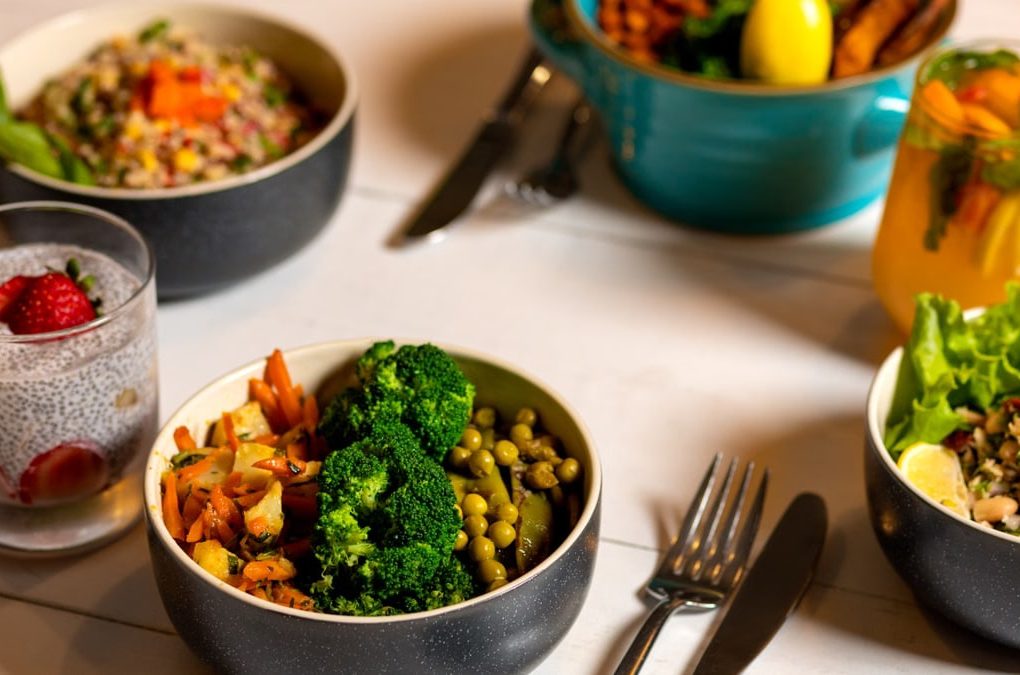 Delicious colorful bowls of salad and fresh beverages on a white table, perfect for healthy dining.