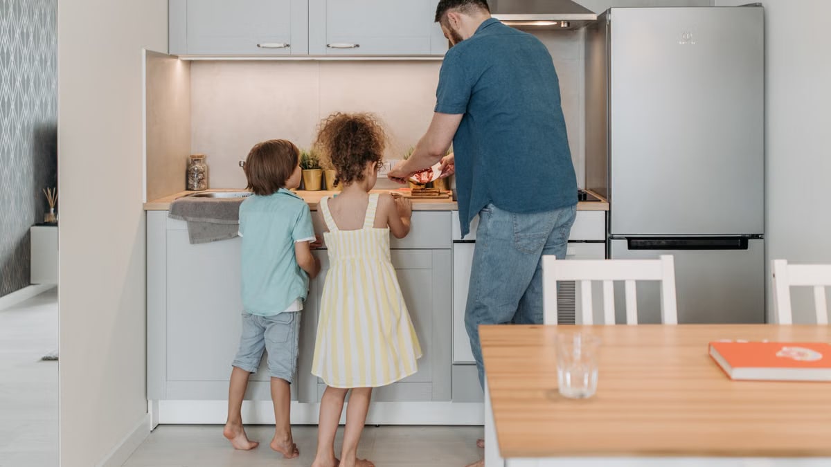 Father and children cooking together in a modern kitchen, enjoying family time.